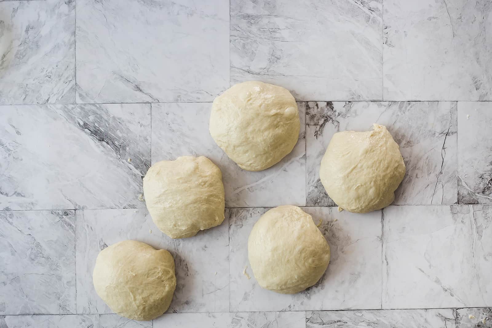 Las bolas de masa para hacer pan naan en una mesa.